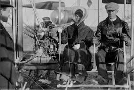 Katherine about to fly for the first time with Wilbur. Her long skirts were tied with rope.